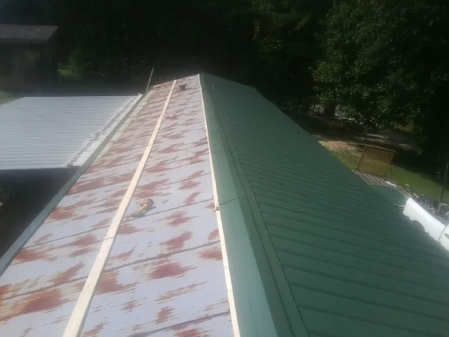 Old rusted panels beside newly installed green metal roofing — Wind Damage Roof Repair by Roofing Brothers in Westfield