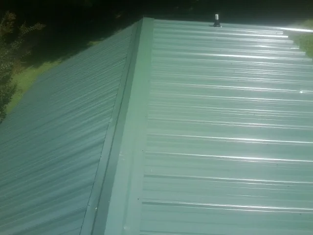 New green metal panels meeting at the ridge of a roof — Flat Roof Repair work by our crew in Westfield